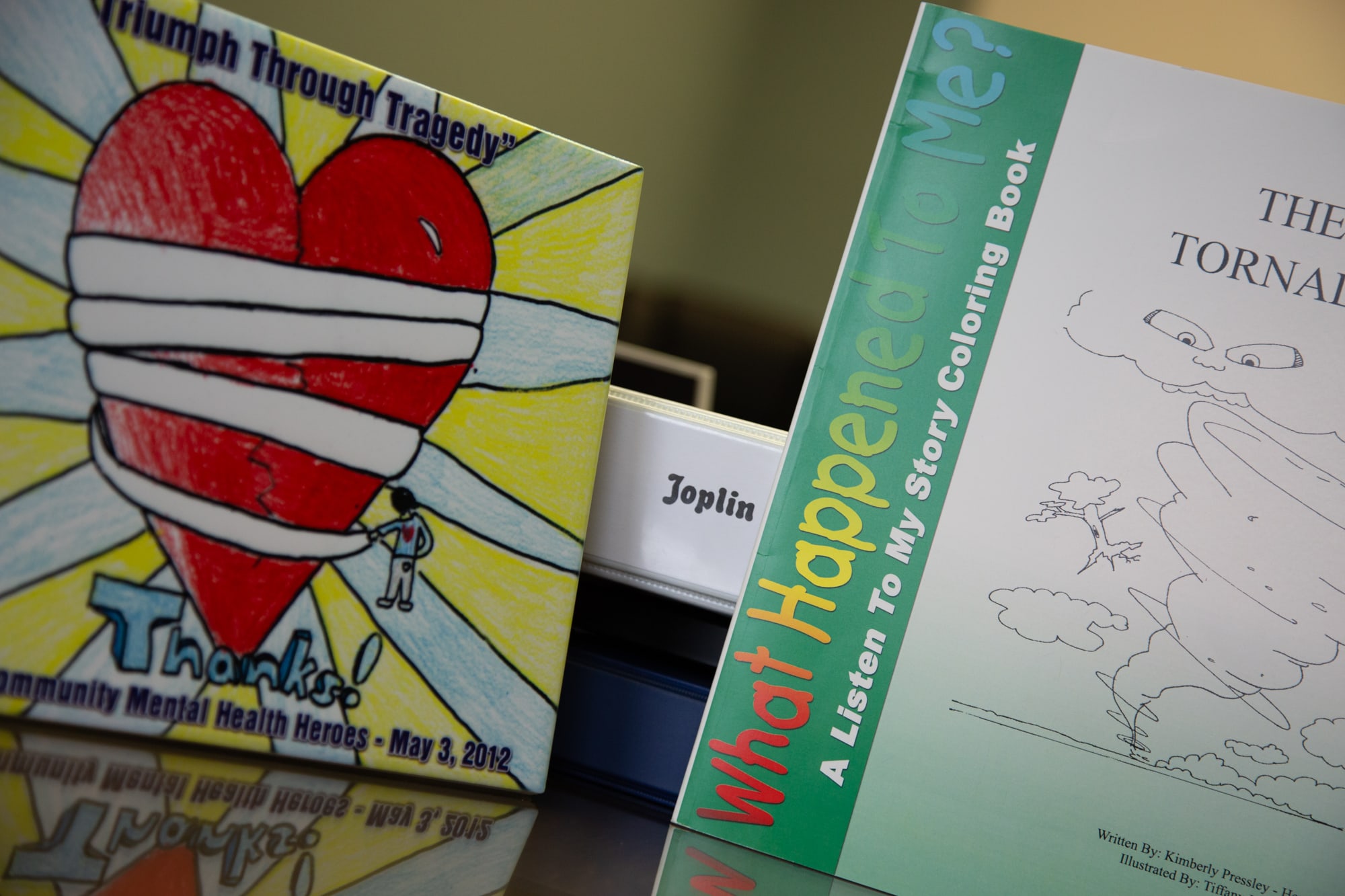 The Healing Joplin program included a coloring book to help young children  process how a tornado can affect them. To the left is a tile depicting a child’s drawing that was submitted in a Healing Joplin art contest. (Brigette Waltermire/News21)